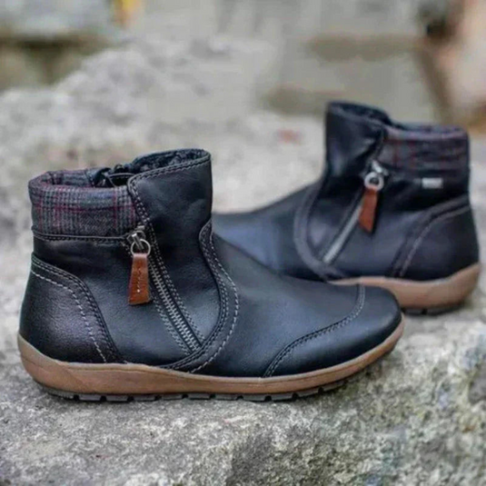 Schwarze Damen-Winterstiefel mit Reißverschluss, rutschfeste Sohle, warm gefüttert, auf grauem Stein. Ideal für kaltes Wetter und Outdoor-Aktivitäten.