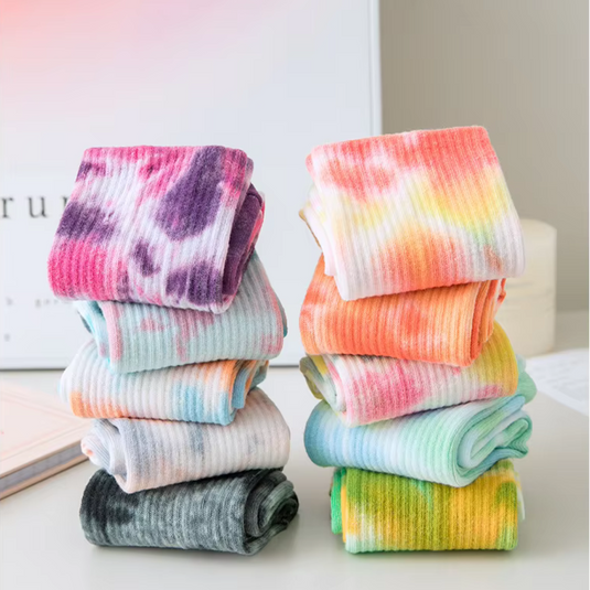 Bunte, gefaltete Socken im Batikmuster auf einem Tisch. Modische, farbenfrohe Socken für Damen und Herren. Trendige Accessoires für den Alltag.
