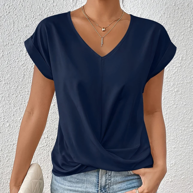 Laden Sie das Bild in Galerie -Viewer, Damenbluse in Dunkelblau mit V-Ausschnitt und kurzen Ärmeln, kombiniert mit Jeans. Elegante Freizeitmode, ideal für Sommeroutfits.

