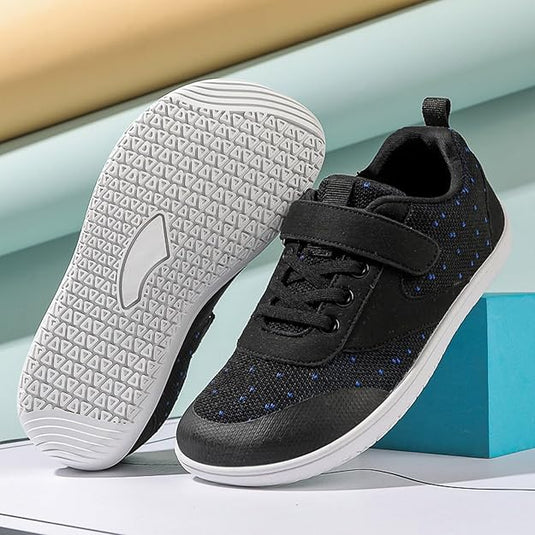 Schwarze Kindersneaker mit Klettverschluss und blauen Punkten, weiße rutschfeste Sohle, modisch und bequem, ideal für Alltag und Sport.