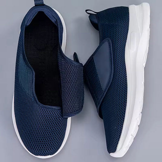 Dunkelblaue Slip-On-Sneaker mit Mesh-Obermaterial und weißer Sohle auf grauem Hintergrund. Bequeme, atmungsaktive Freizeitschuhe für Herren.