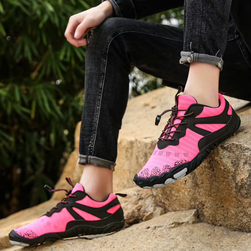 Laden Sie das Bild in Galerie -Viewer, Person trägt pinke Wanderschuhe mit schwarzem Muster, sitzt auf Felsen. Outdoor-Schuhe, atmungsaktiv, rutschfest, ideal für Trekking und Wandern.
