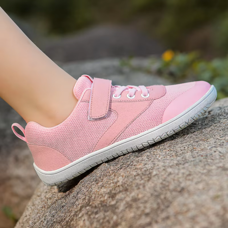 Laden Sie das Bild in Galerie -Viewer, Rosa Damen-Sneaker mit Klettverschluss und weißer Sohle auf einem Felsen, ideal für Outdoor-Aktivitäten und Freizeitmode.
