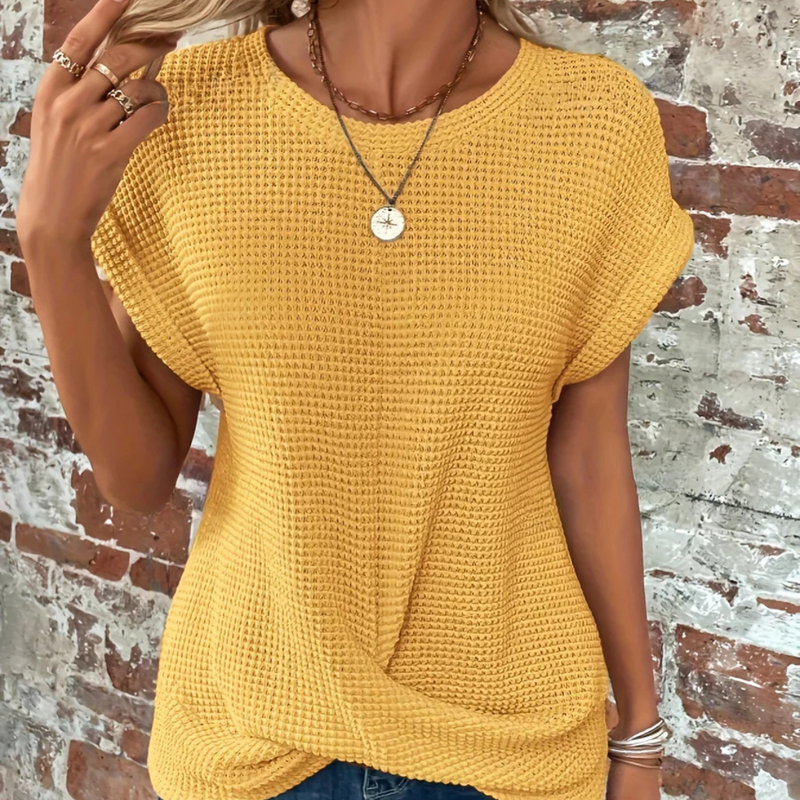 Laden Sie das Bild in Galerie -Viewer, Frau in gelbem Strickpullover vor Backsteinwand, trägt Halskette und Ringe. Modetrend, lässiger Stil, Sommeroutfit, Damenmode.
