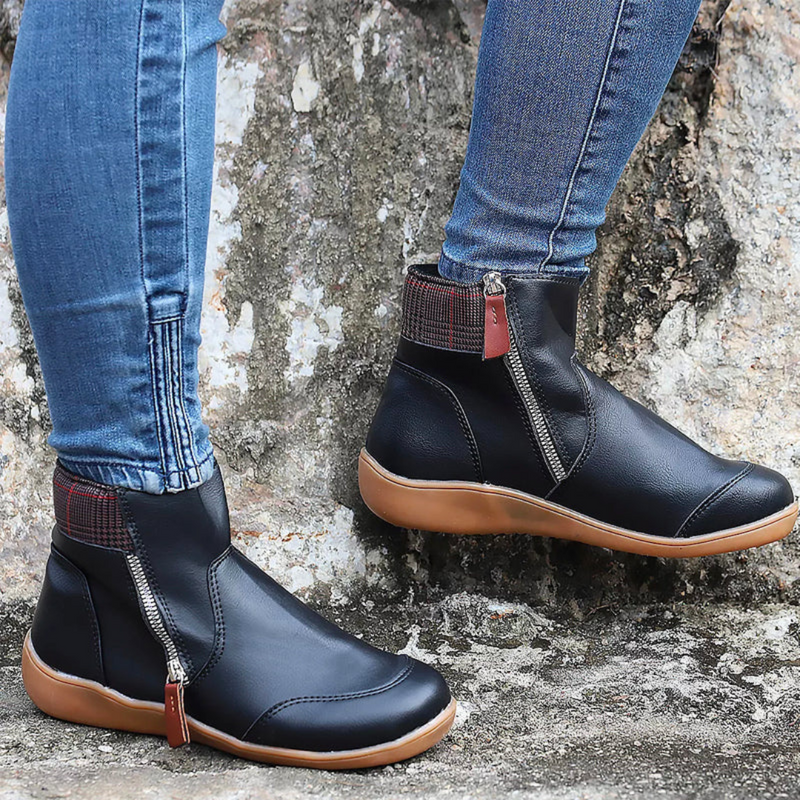 Laden Sie das Bild in Galerie -Viewer, Damenstiefel mit Reißverschluss, schwarze Lederoptik, braune Sohle, getragen mit blauen Jeans, Outdoor-Hintergrund, modische Herbstschuhe.
