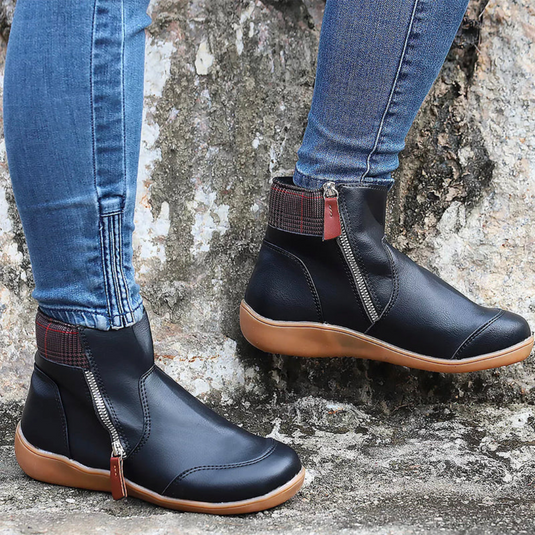 Damenstiefel mit Reißverschluss, schwarze Lederoptik, braune Sohle, getragen mit blauen Jeans, Outdoor-Hintergrund, modische Herbstschuhe.