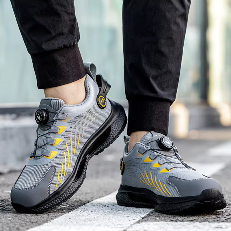 Laden Sie das Bild in Galerie -Viewer, Graue und gelbe Sportschuhe mit modernem Design auf Asphalt, getragen von einer Person in schwarzer Hose. Bequeme Laufschuhe, ideal für Outdoor-Aktivitäten.
