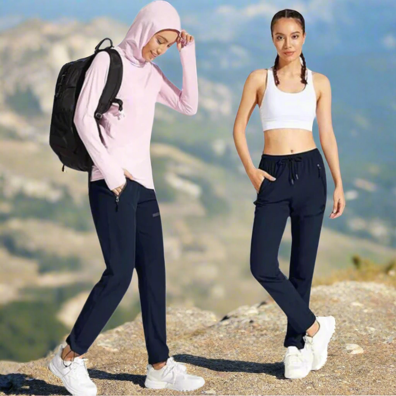 Laden Sie das Bild in Galerie -Viewer, Zwei Frauen in Sportbekleidung stehen in einer Berglandschaft. Eine trägt ein rosa Hoodie und Rucksack, die andere ein weißes Top. Outdoor, Fitness, Wandern.
