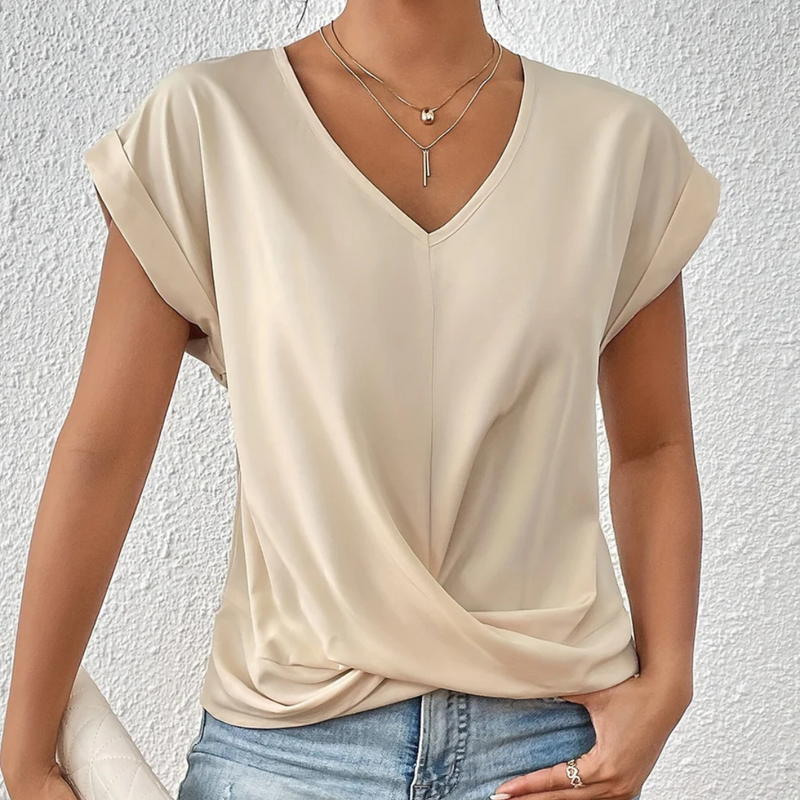Laden Sie das Bild in Galerie -Viewer, Damenbluse in Beige mit V-Ausschnitt und kurzen Ärmeln, kombiniert mit blauer Jeans. Elegante Sommermode, ideal für Freizeit und Büro.
