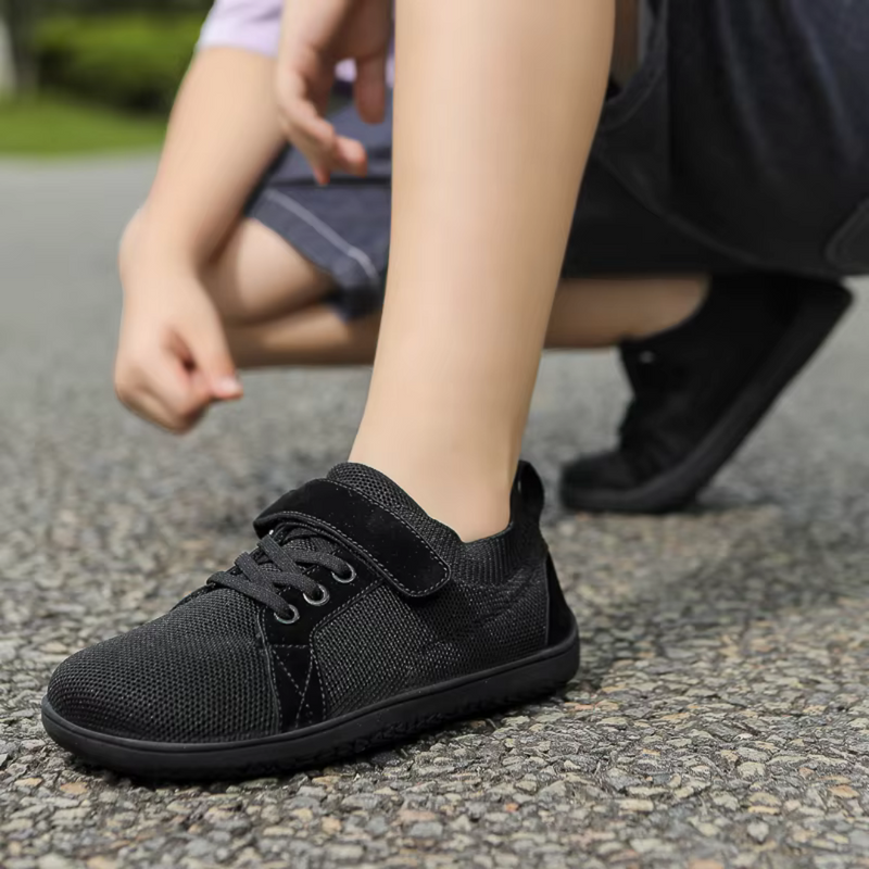 Laden Sie das Bild in Galerie -Viewer, Junge bindet schwarze Kinderschuhe mit Klettverschluss auf Asphalt. Bequeme, atmungsaktive Sneakers für Kinder. Outdoor-Aktivitäten, Freizeit.
