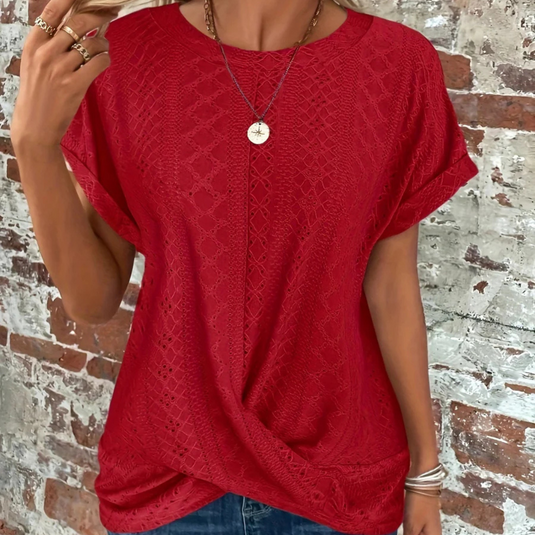 Rotes Damen-Spitzenshirt vor Backsteinwand, lässiger Stil, kurze Ärmel, modisches Design, ideal für Sommermode und Freizeitkleidung.