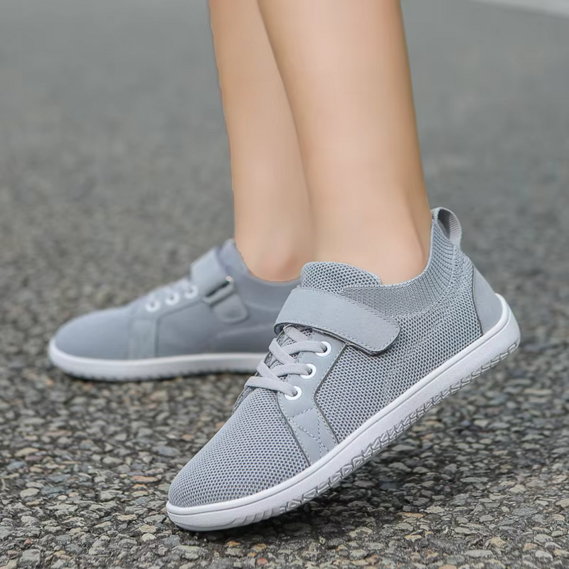 Laden Sie das Bild in Galerie -Viewer, Graue Sneaker auf Asphalt, atmungsaktives Mesh-Design, Klettverschluss, ideal für Laufen und Freizeit. Bequeme Sportschuhe für Damen.
