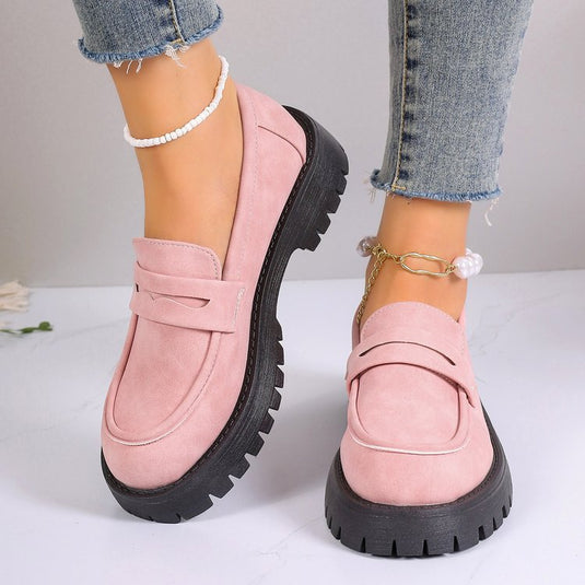 Rosa Damen-Loafer mit dicker schwarzer Sohle, getragen mit blauen Jeans und Perlenfußkettchen. Modische Schuhe, bequeme Damenmode.